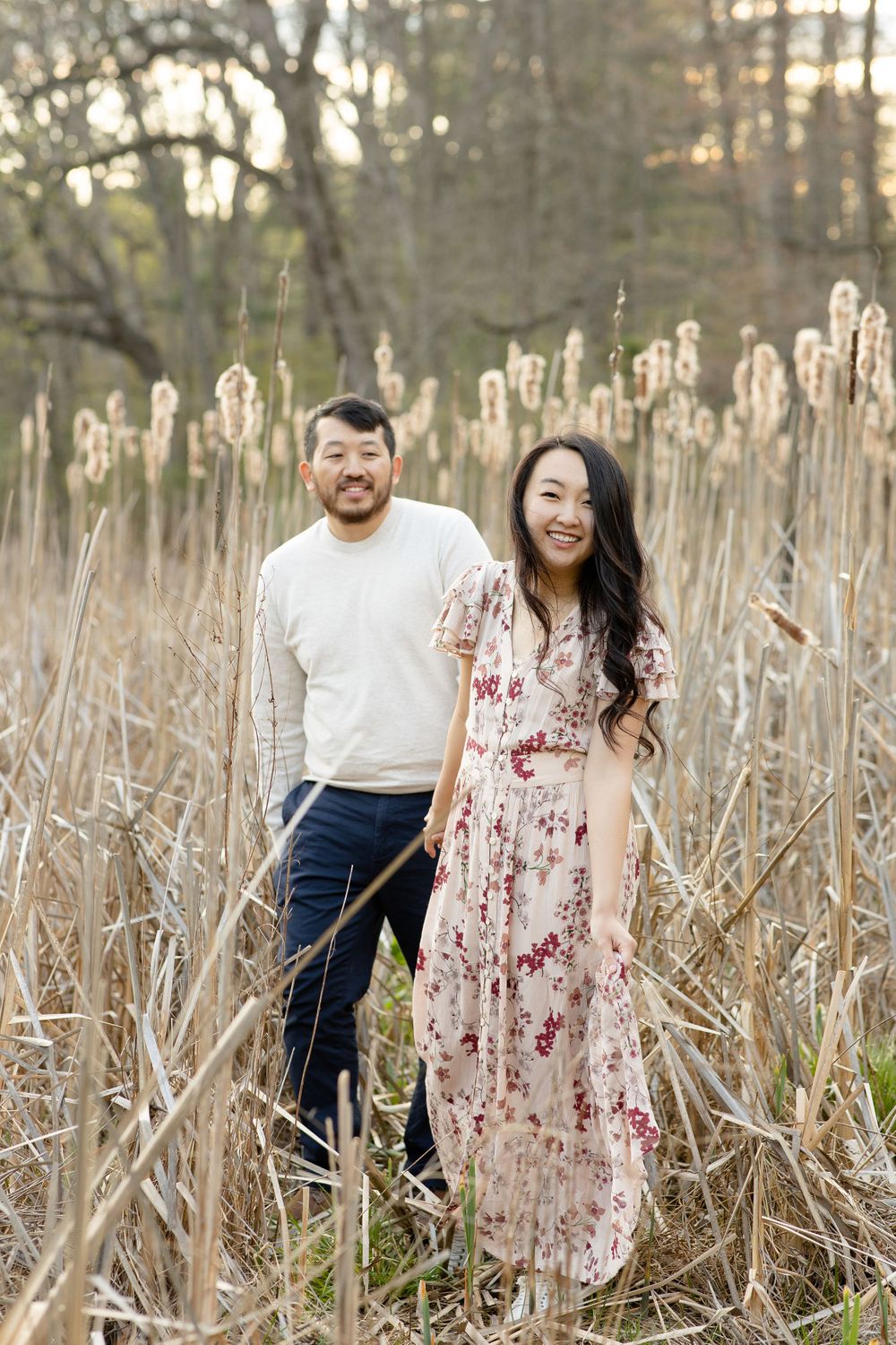 A romantic couple poses in a field of tall cattails during golden hour.
