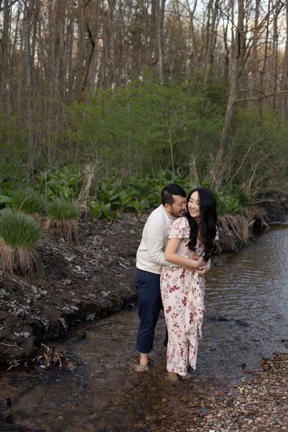Romantic couple embracing while standing in a woodland stream.
