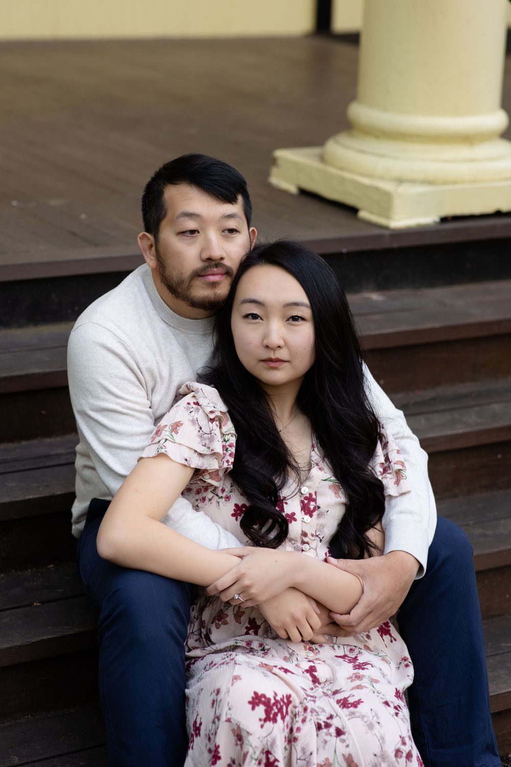 A couple sits close together on wooden steps during an outdoor portrait session.