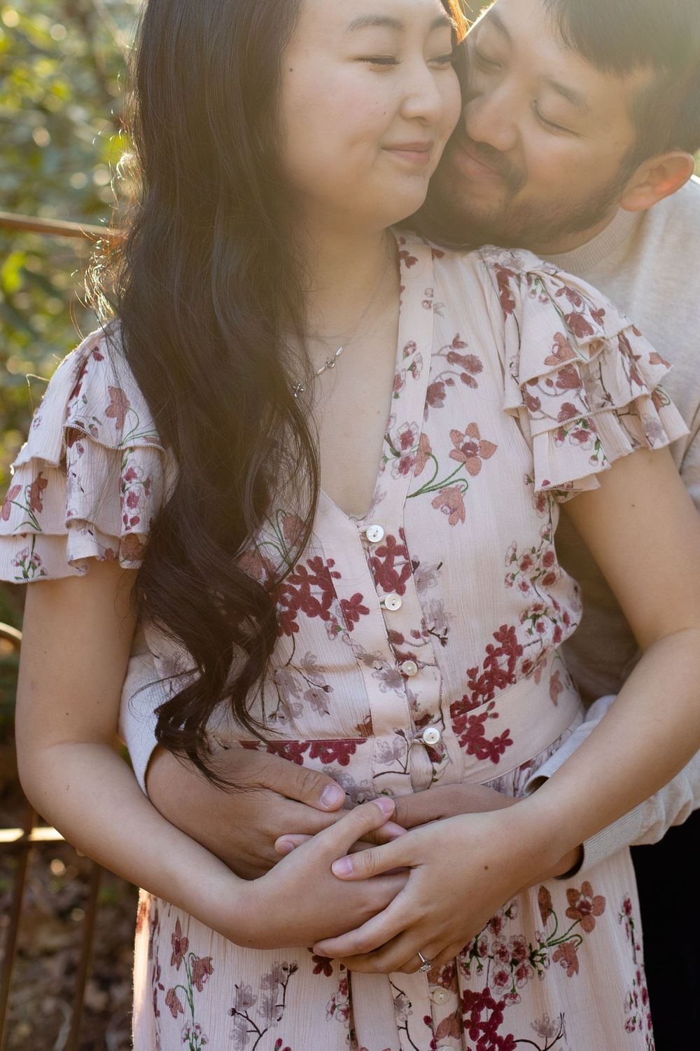 A couple shares a tender embrace in warm sunlight during an outdoor photo session.