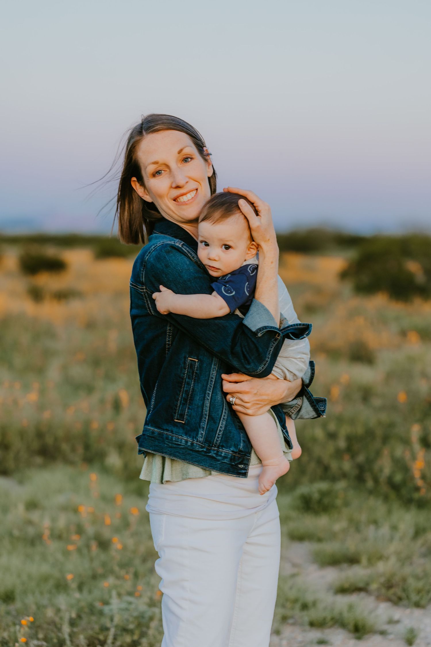 Mother and baby sharing tender moment in desert setting at dusk.
