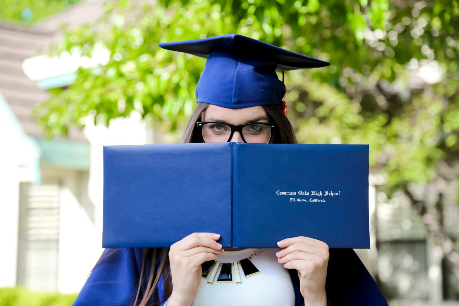 cohs graduate hiding behind diploma