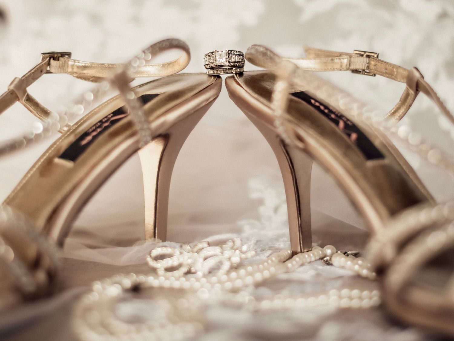 Wedding rings artistically arranged on lace with elegant bridal accessories.