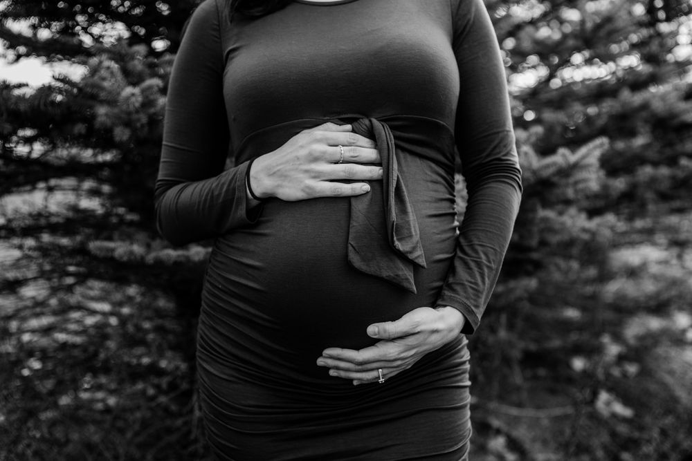 A black and white maternity portrait series shows growing belly with hands tenderly placed on the bump.