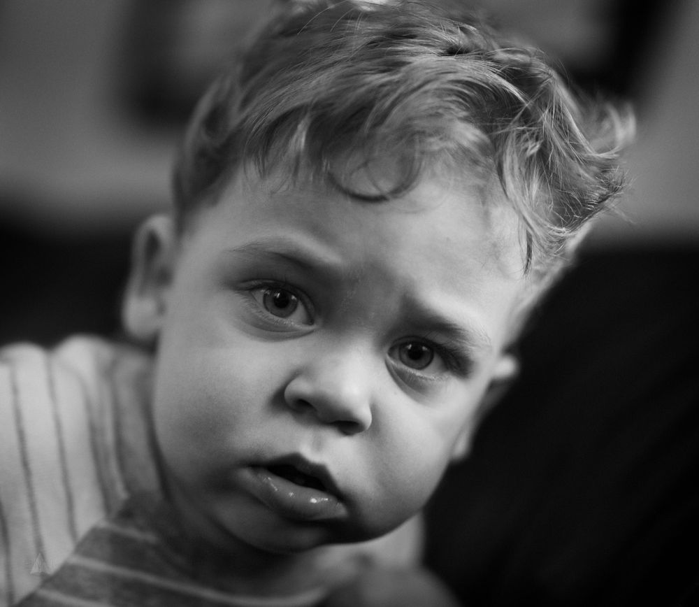 Black and white portrait of small child with tousled hair and thoughtful expression.
