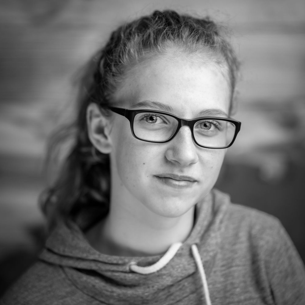 Black and white portrait of person wearing glasses with hair pulled back.