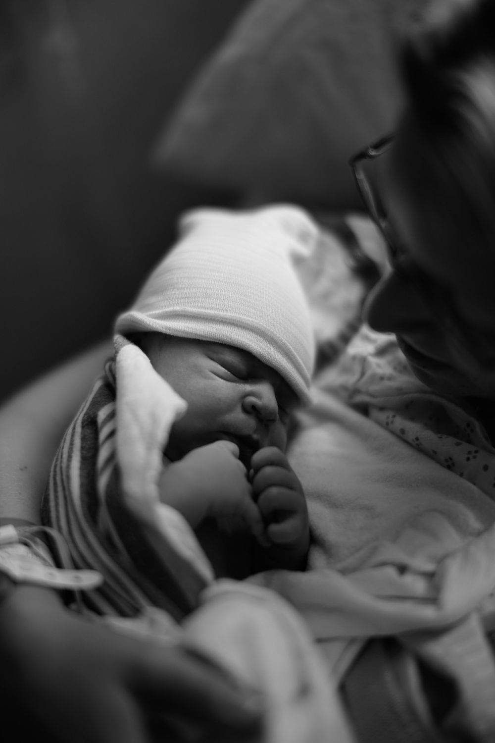 Black and white close-up of tiny infant feet wrapped in striped blanket.