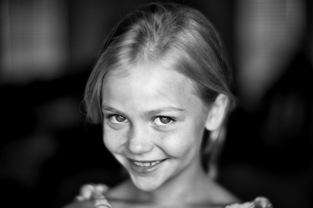 Black and white close-up portrait showing a bright cheerful expression.
