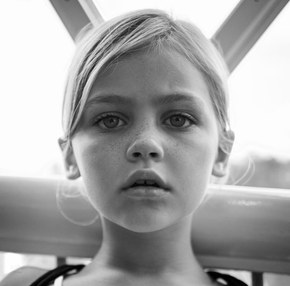 Black and white portrait of a young child with striking eyes looking directly at camera.