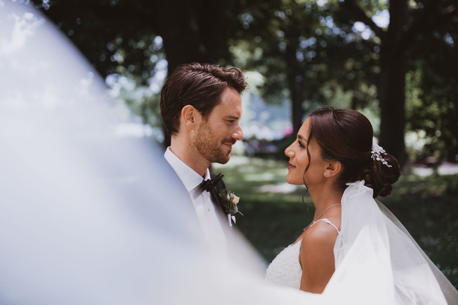 A romantic wedding moment captured in soft lighting under trees.