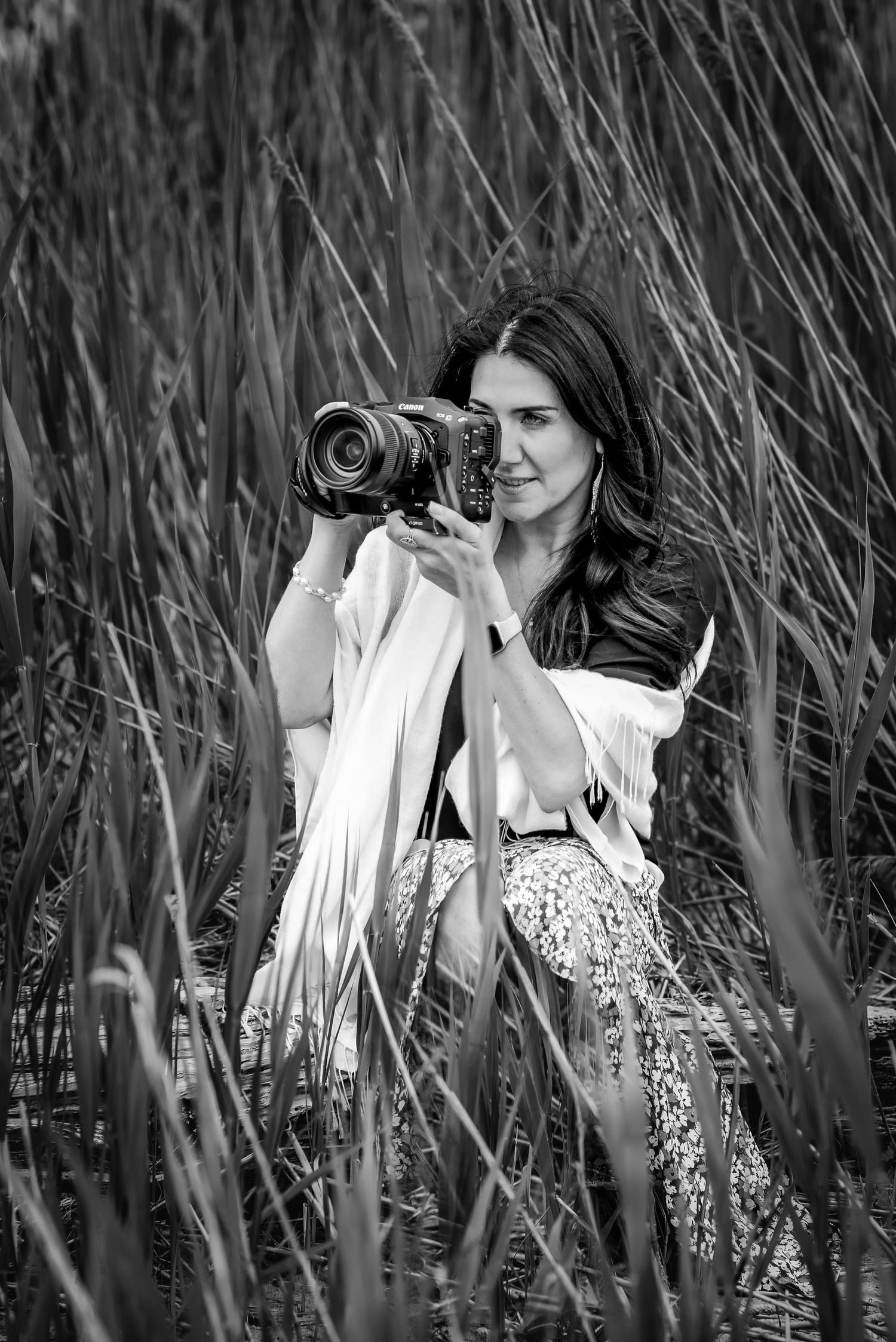 Studio Rivy Founder and Owner takes picture squatting in tall grass at Clinton Beach