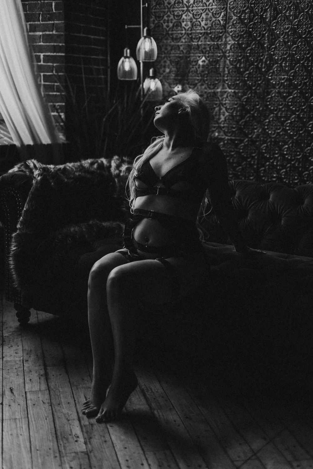 Black and white boudoir portrait with pendant lights and vintage furniture.