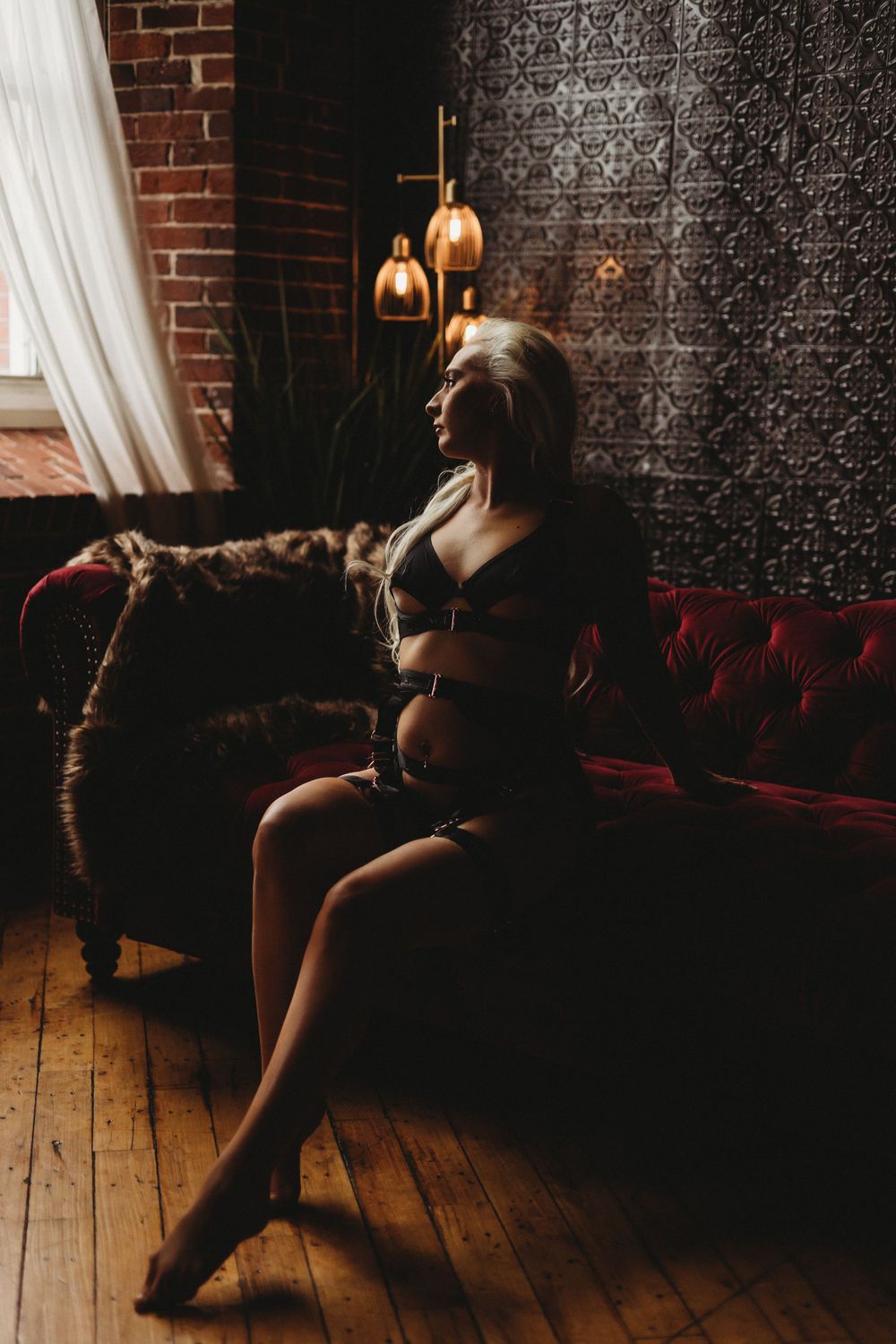 Dramatic portrait on vintage couch with exposed brick and decorative lighting.