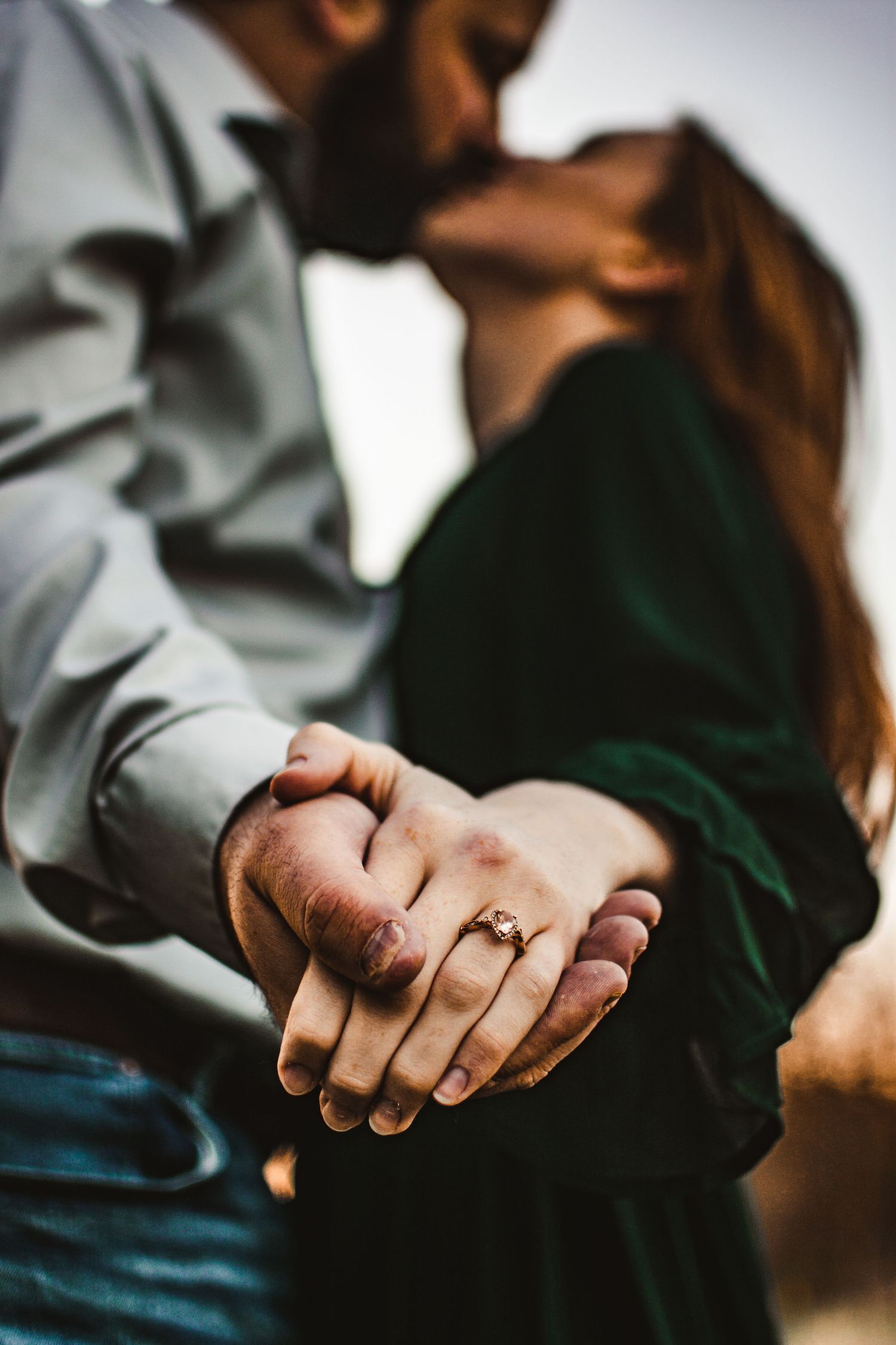 Close-up shot of intertwined hands with an engagement ring in soft focus.