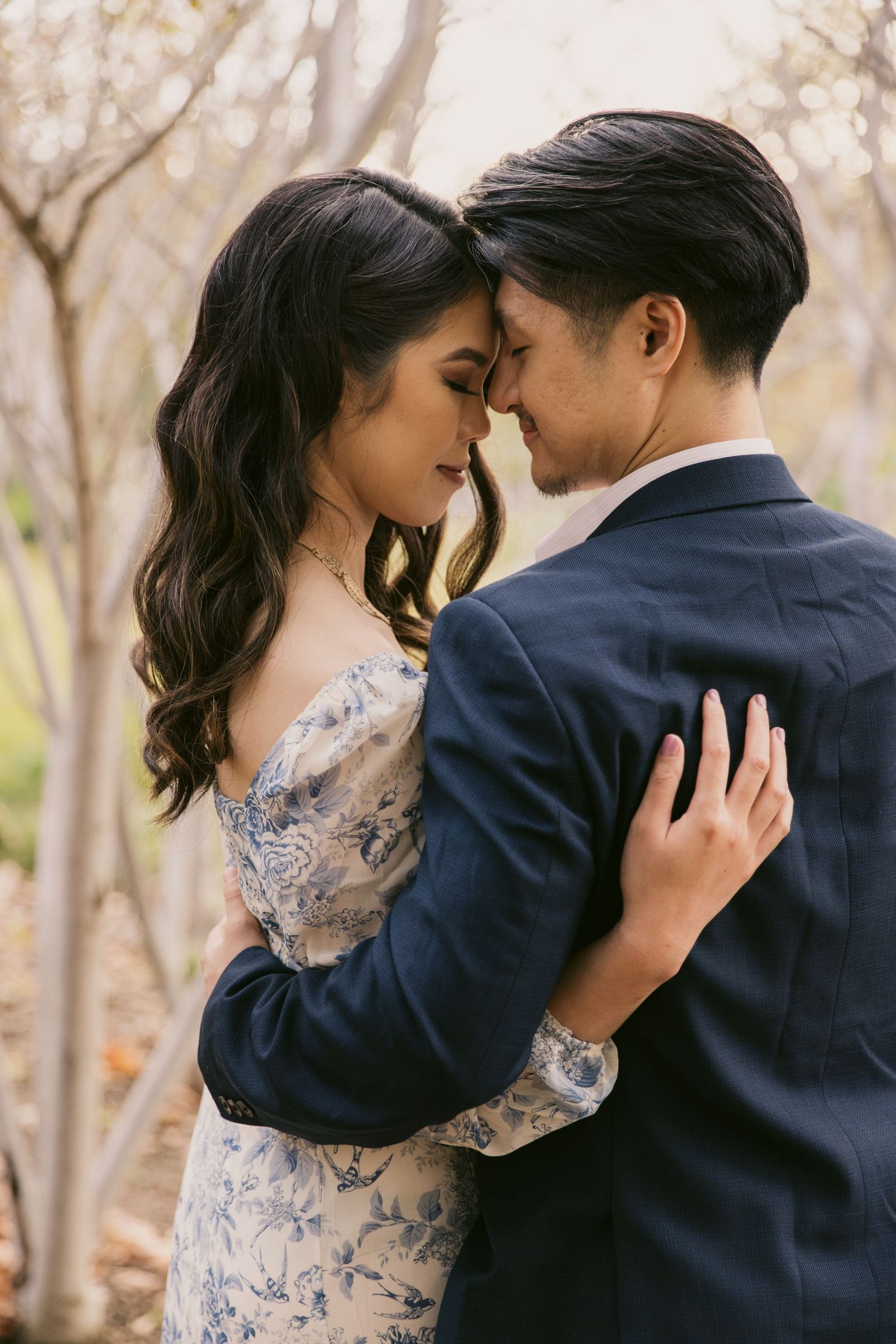 A tender moment between a couple in formal attire surrounded by fall foliage.