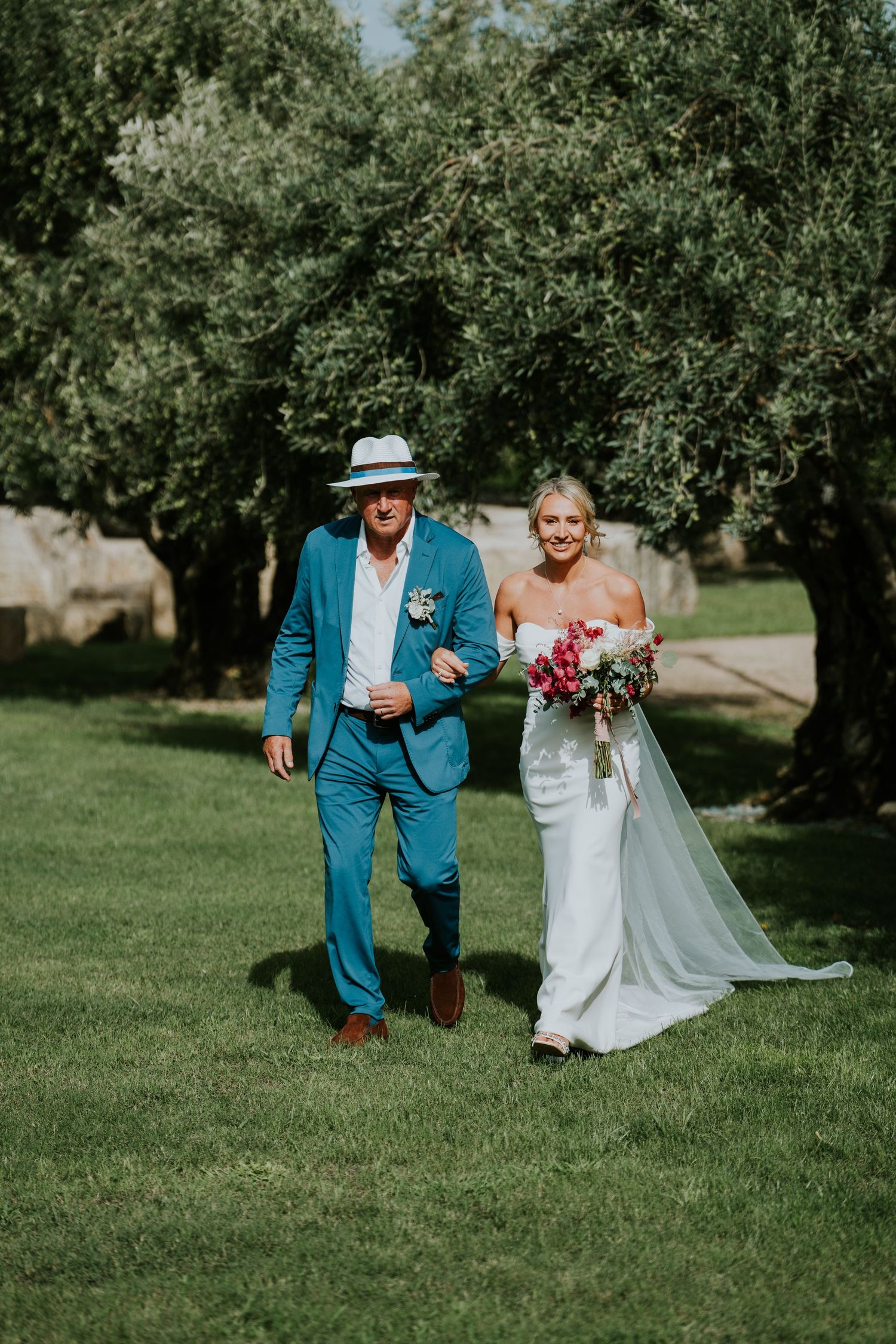 Wedding processional on a lush green lawn with vibrant floral decorations.