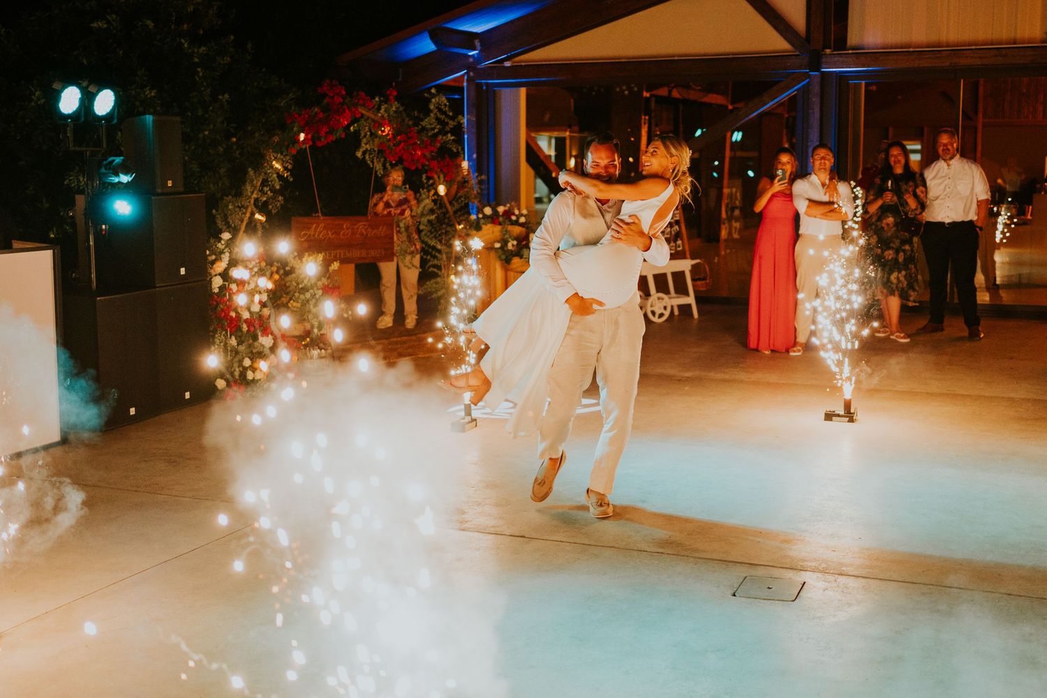 Couples dancing on an illuminated outdoor patio during evening wedding festivities.