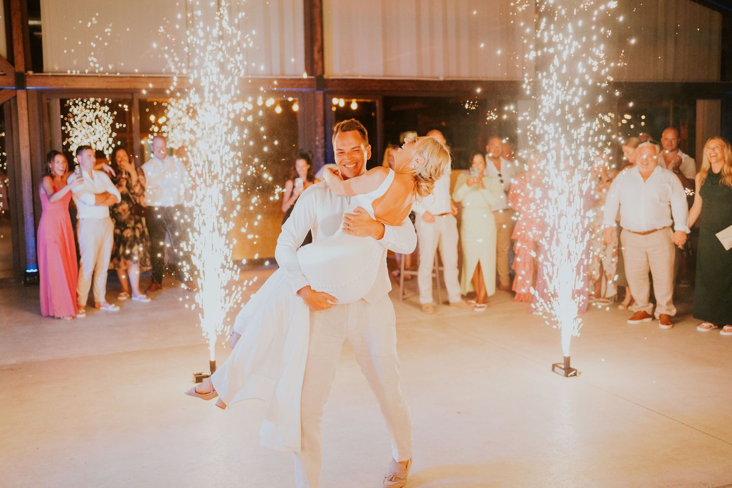 A couple performs their first dance at a wedding reception with sparklers creating a magical atmosphere.