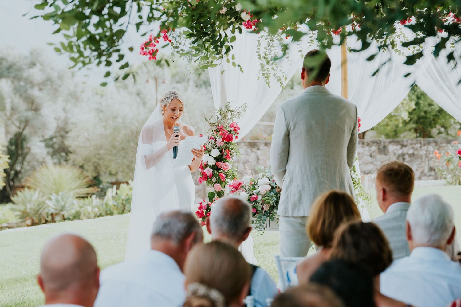 A beautiful outdoor wedding ceremony with pink and white floral decorations.