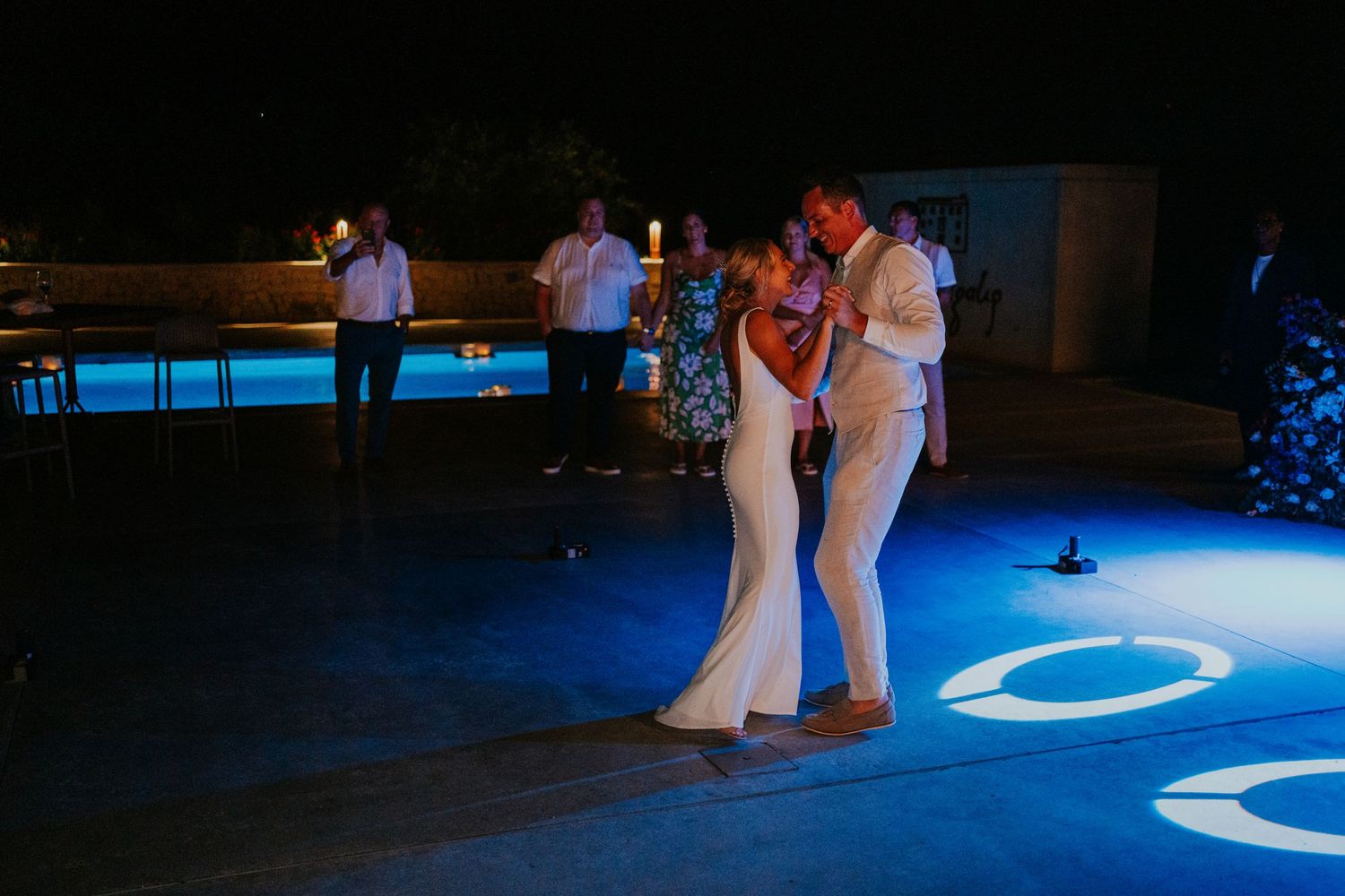 Wedding dancers on a blue-lit dance floor during an evening reception celebration.