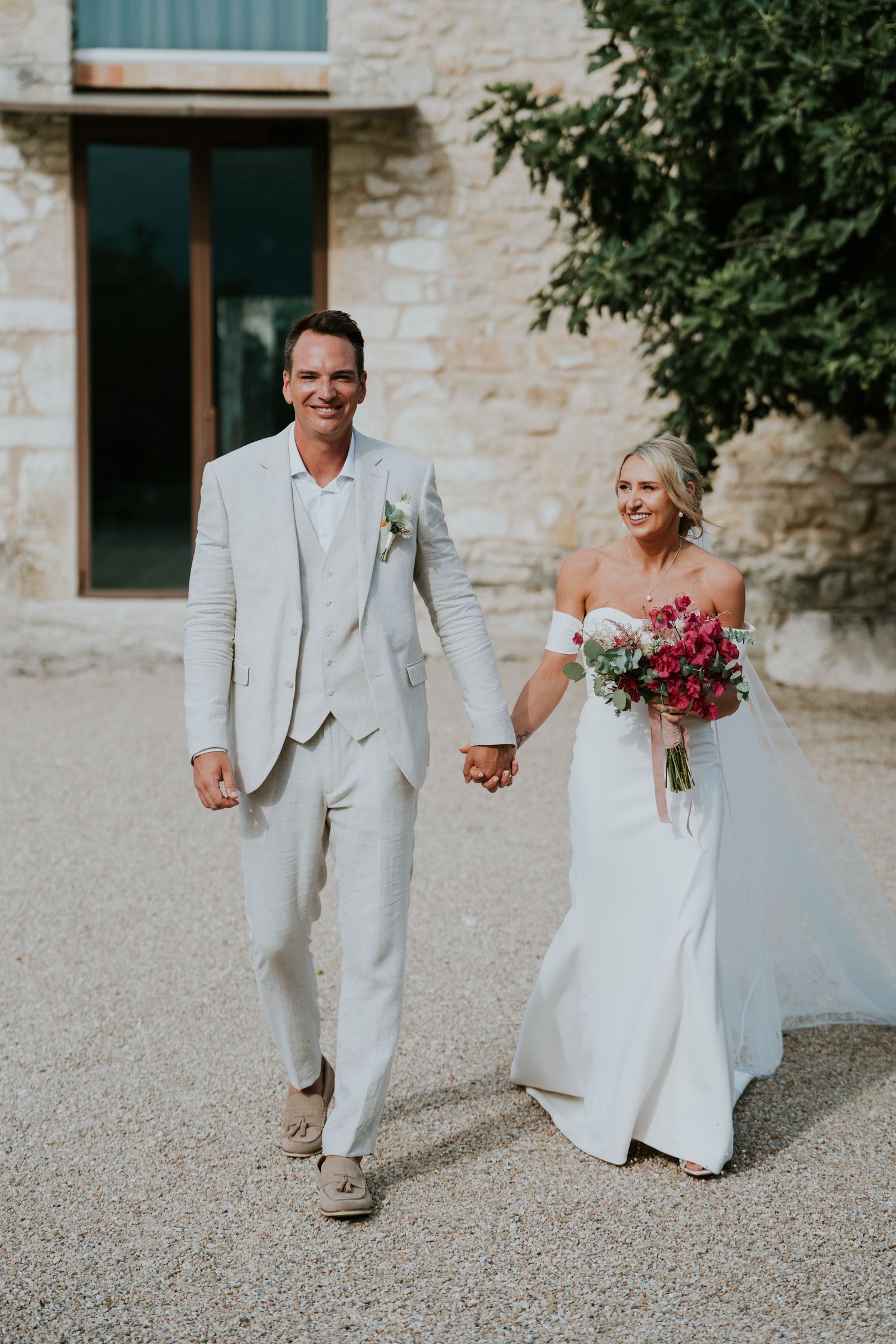 A romantic walk along a stone building on wedding day.