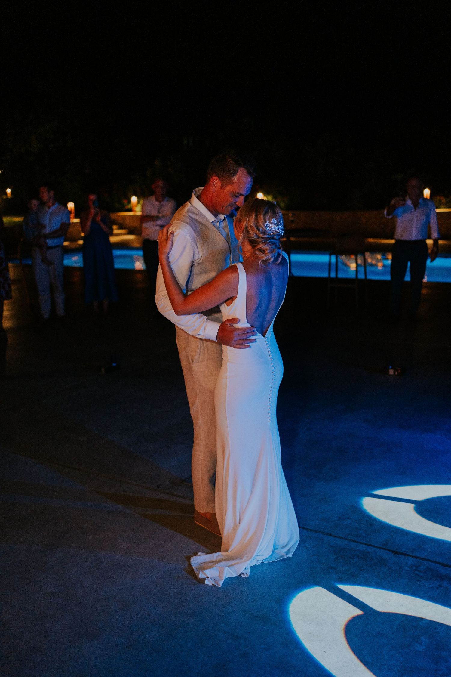 A couple sharing their first dance on an illuminated dance floor at night.