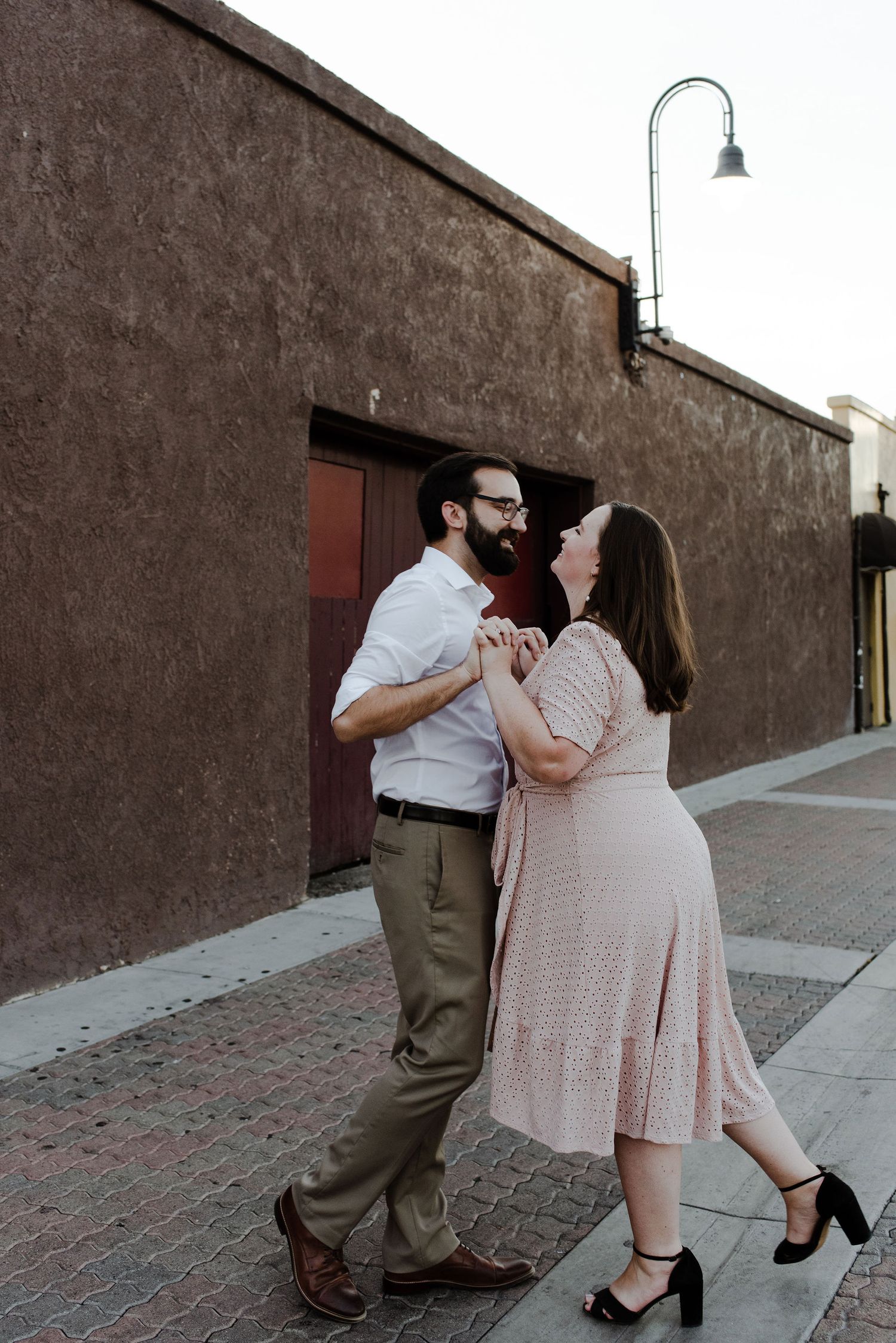 Couple swing dancing in a back alley of downtown Fullerton during their engagement photoshoot.