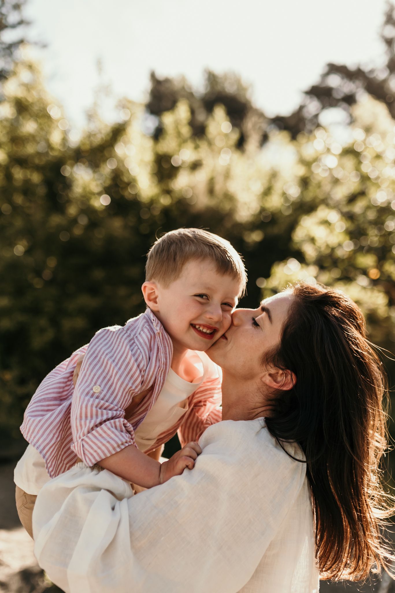 Candid moment of joyful laughter and affection shared during outdoor family photoshoot.