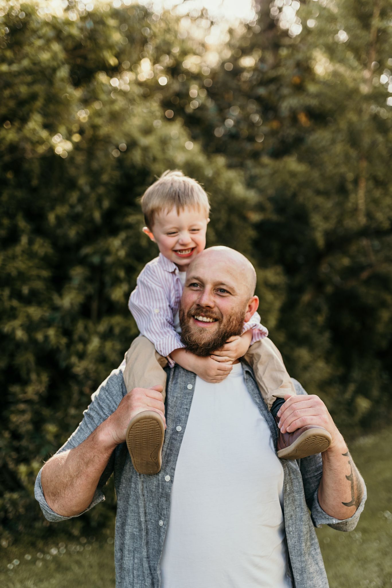 A heartwarming moment of a child riding on shoulders during a sunny outdoor photoshoot.