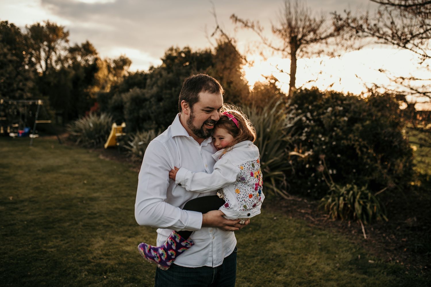 A tender embrace shared between a parent and child at sunset in a garden setting.