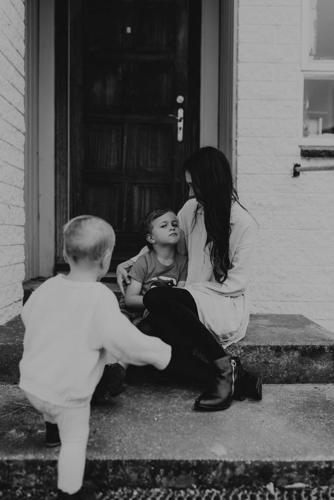 Black and white image of family sitting on front porch steps.