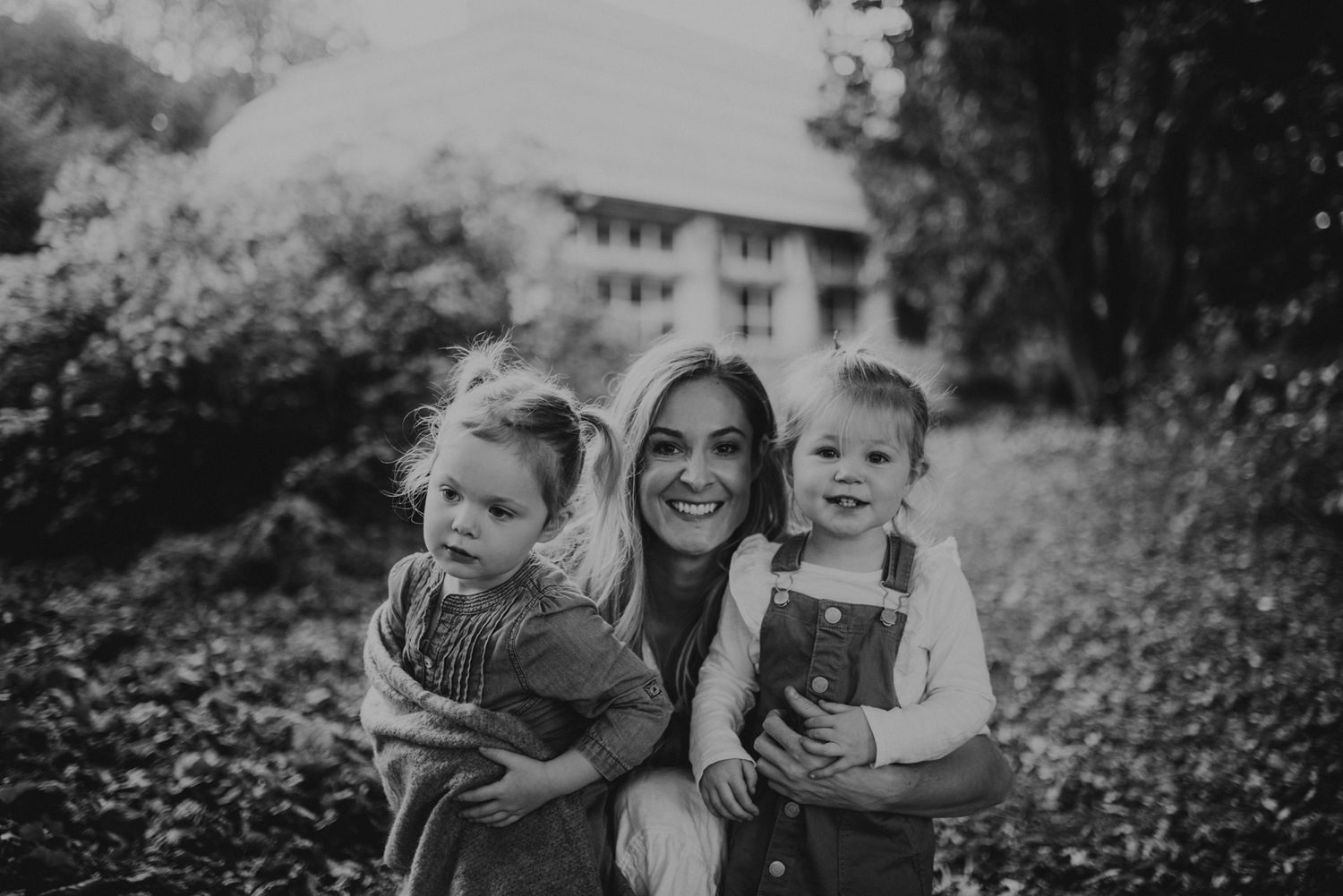 Black and white portrait capturing a tender moment outdoors surrounded by nature.
