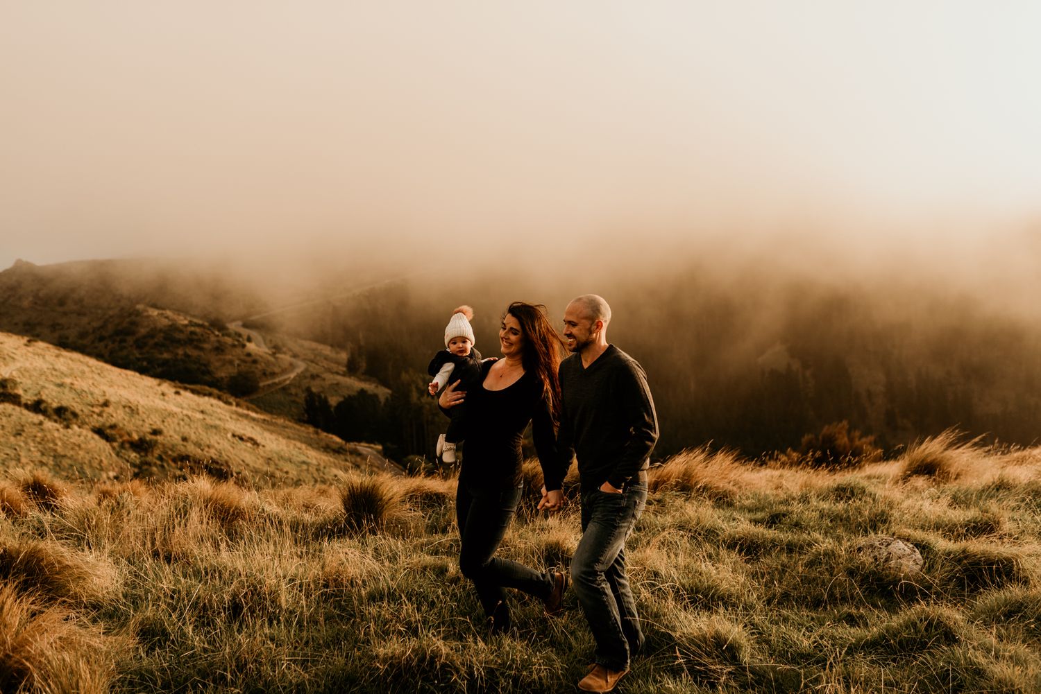 Group hiking through misty mountain terrain with golden grass and foggy atmosphere.