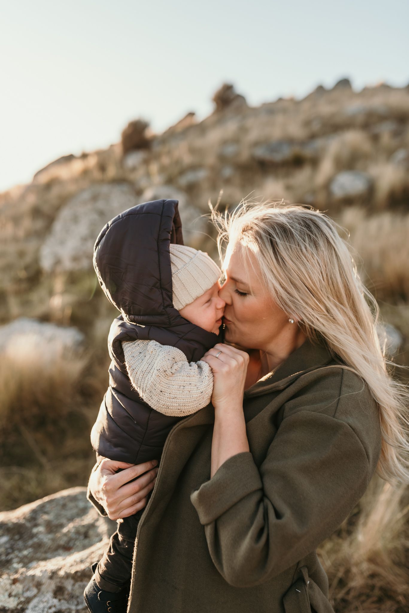 Tender moment between parent and child against rocky natural backdrop.