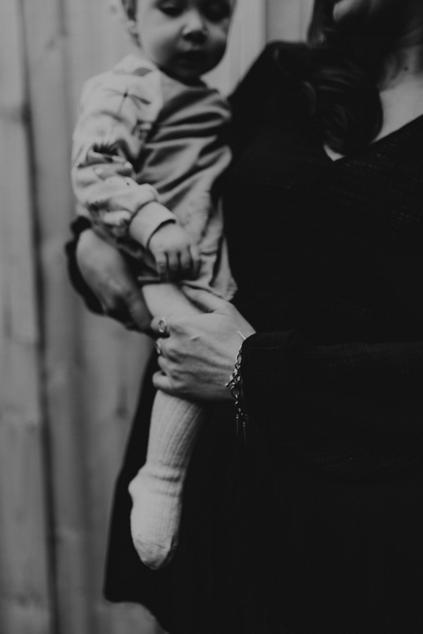 Black and white vintage photo showing a small child being held up with a focus on their sock and leg.