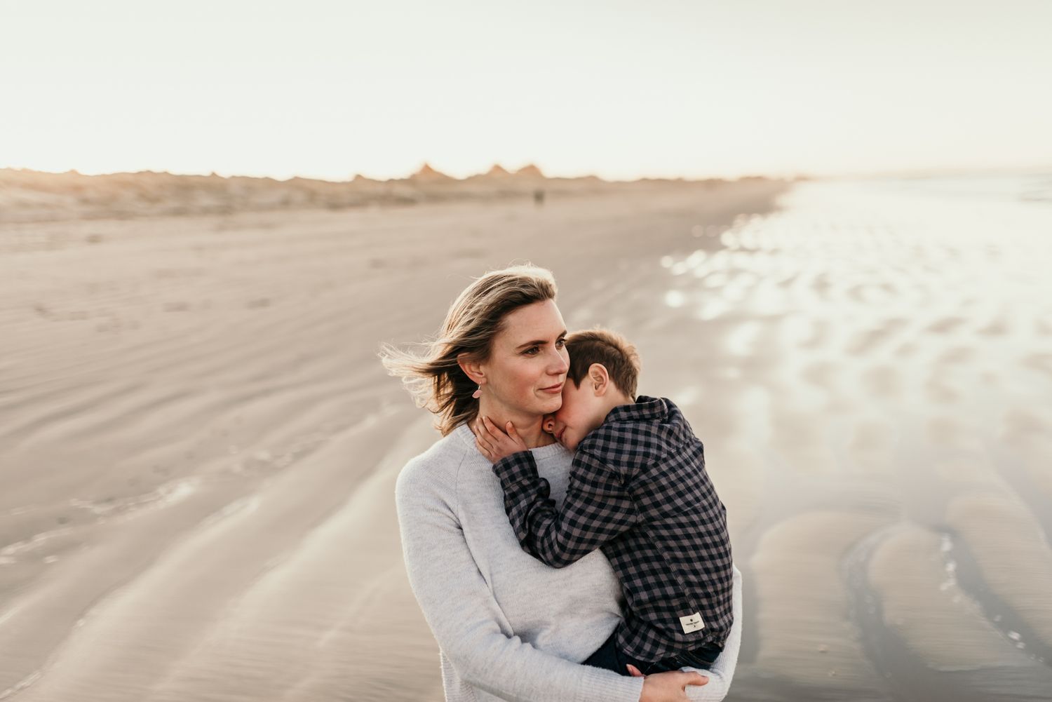 Tender moment between parent and child on sandy beach at sunset.