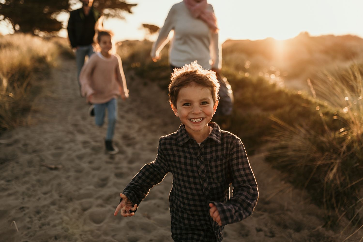 Child running on trail at sunset with silhouettes in background.
