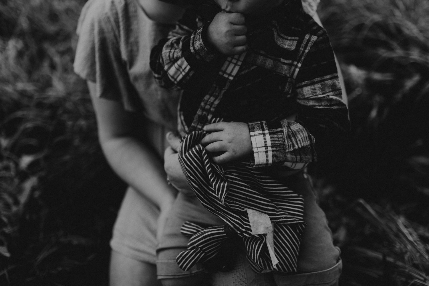Close-up black and white photograph showing hands holding a plaid-patterned fabric.