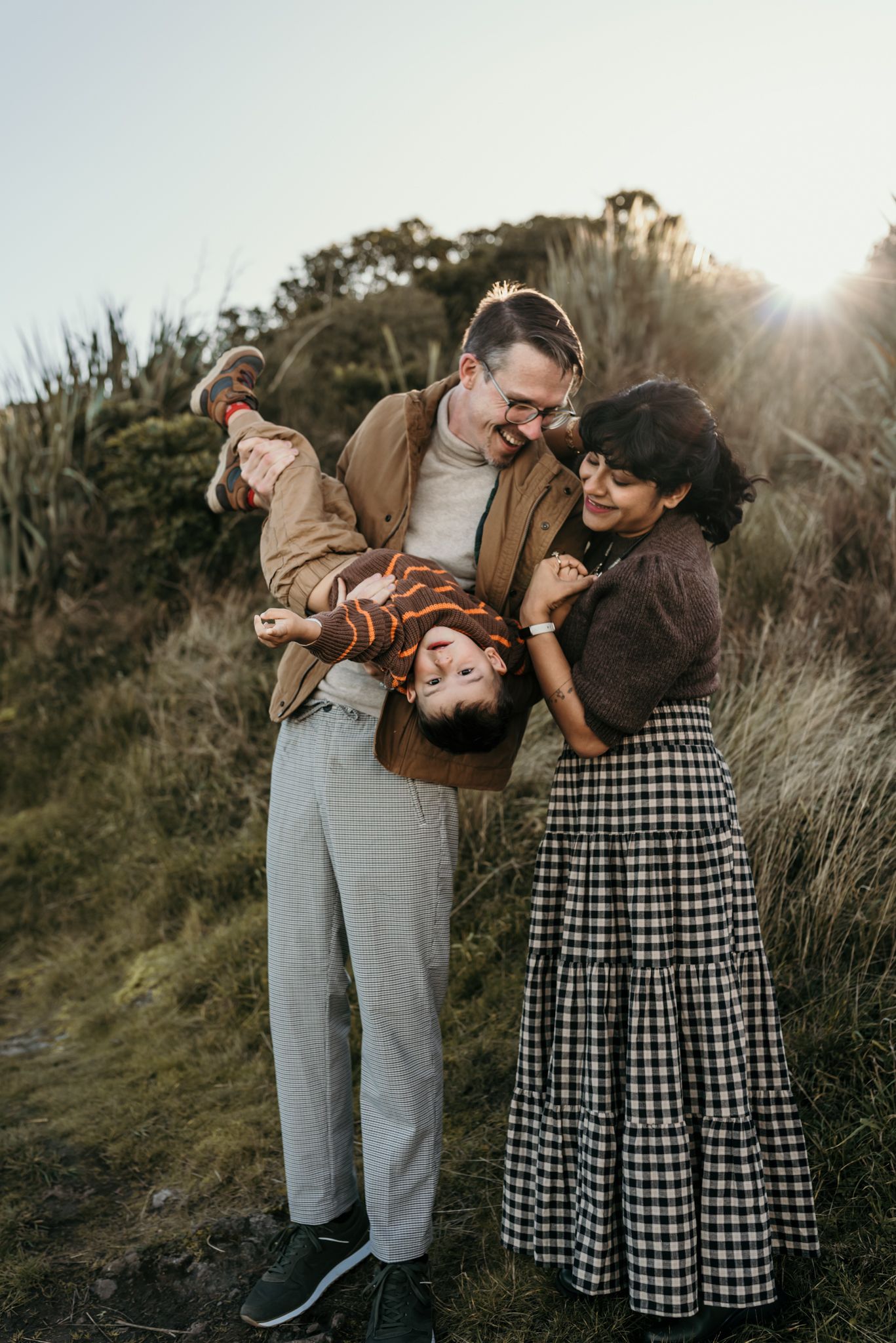 A loving family shares a playful moment together against a scenic natural backdrop at sunset.