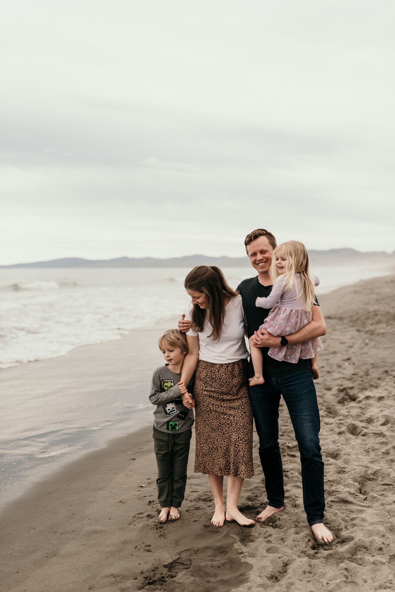 A family enjoying a cloudy day together on a peaceful beach shoreline.