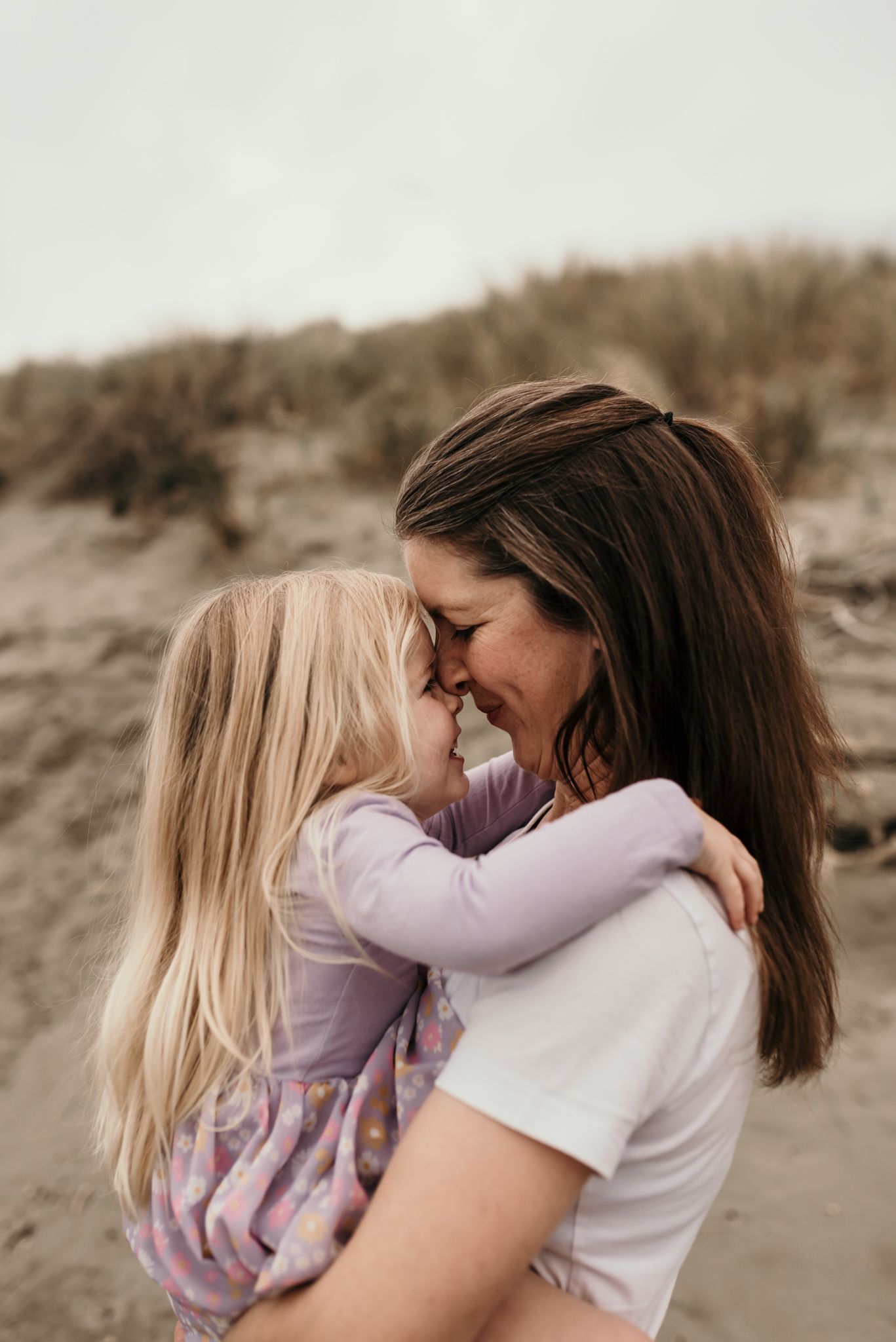 An intimate moment of connection and laughter captured in the sand dunes.