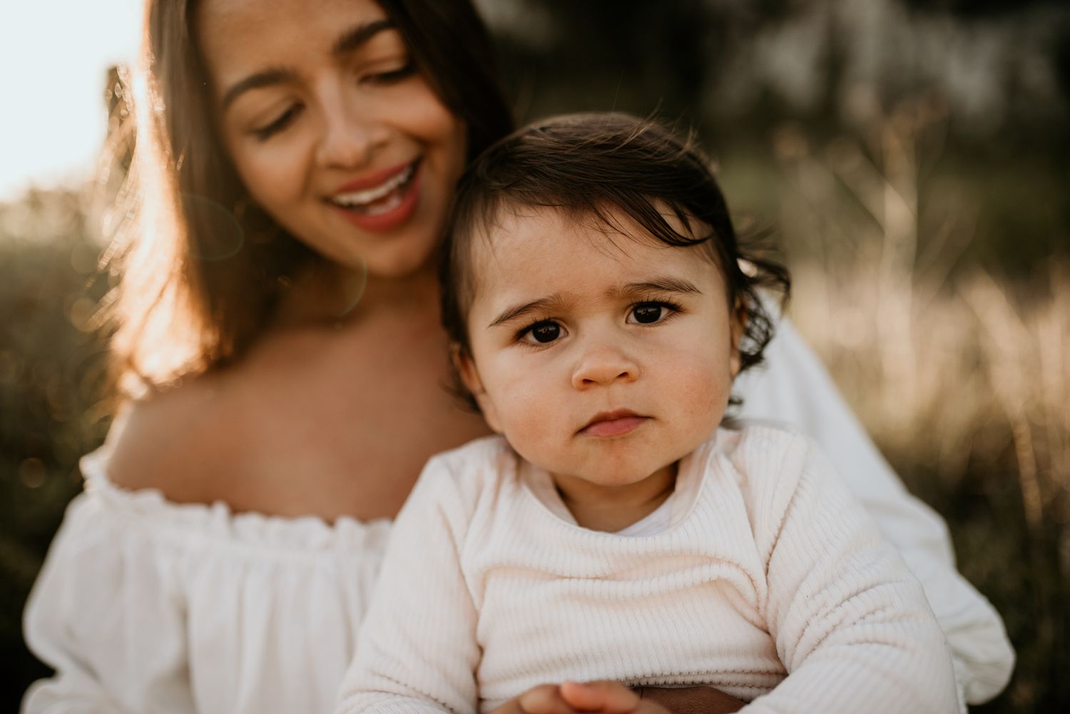 A joyful outdoor portrait of a parent and child wearing matching white outfits.