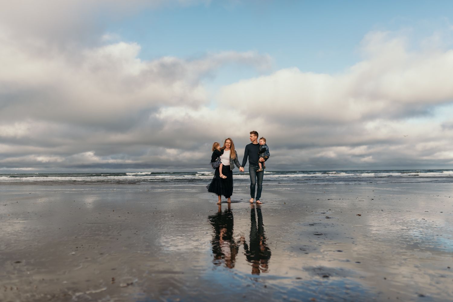 Romantic beach portrait with perfect reflections in wet sand and moody cloudy skies.