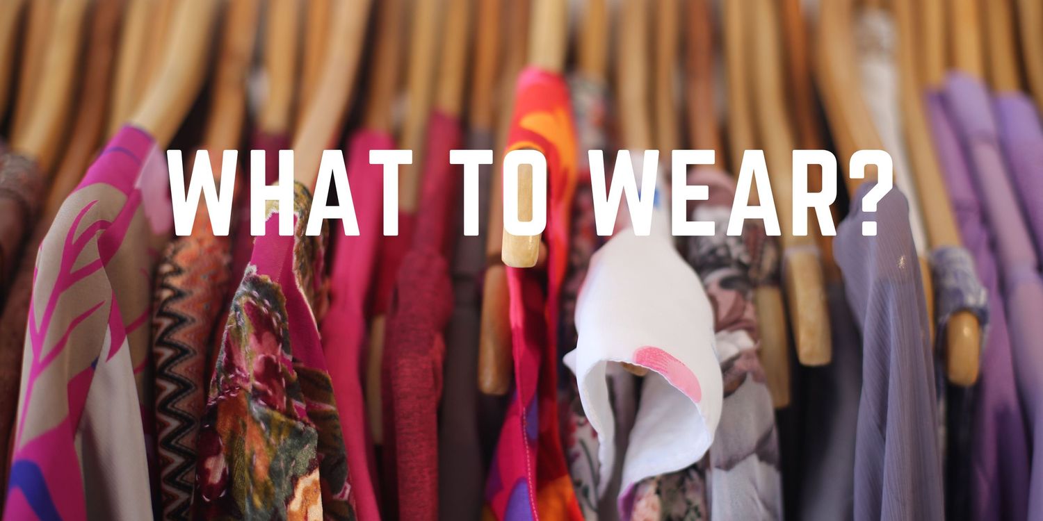 Colorful clothing hanging on wooden hangers on a rack with text reading What To Wear.