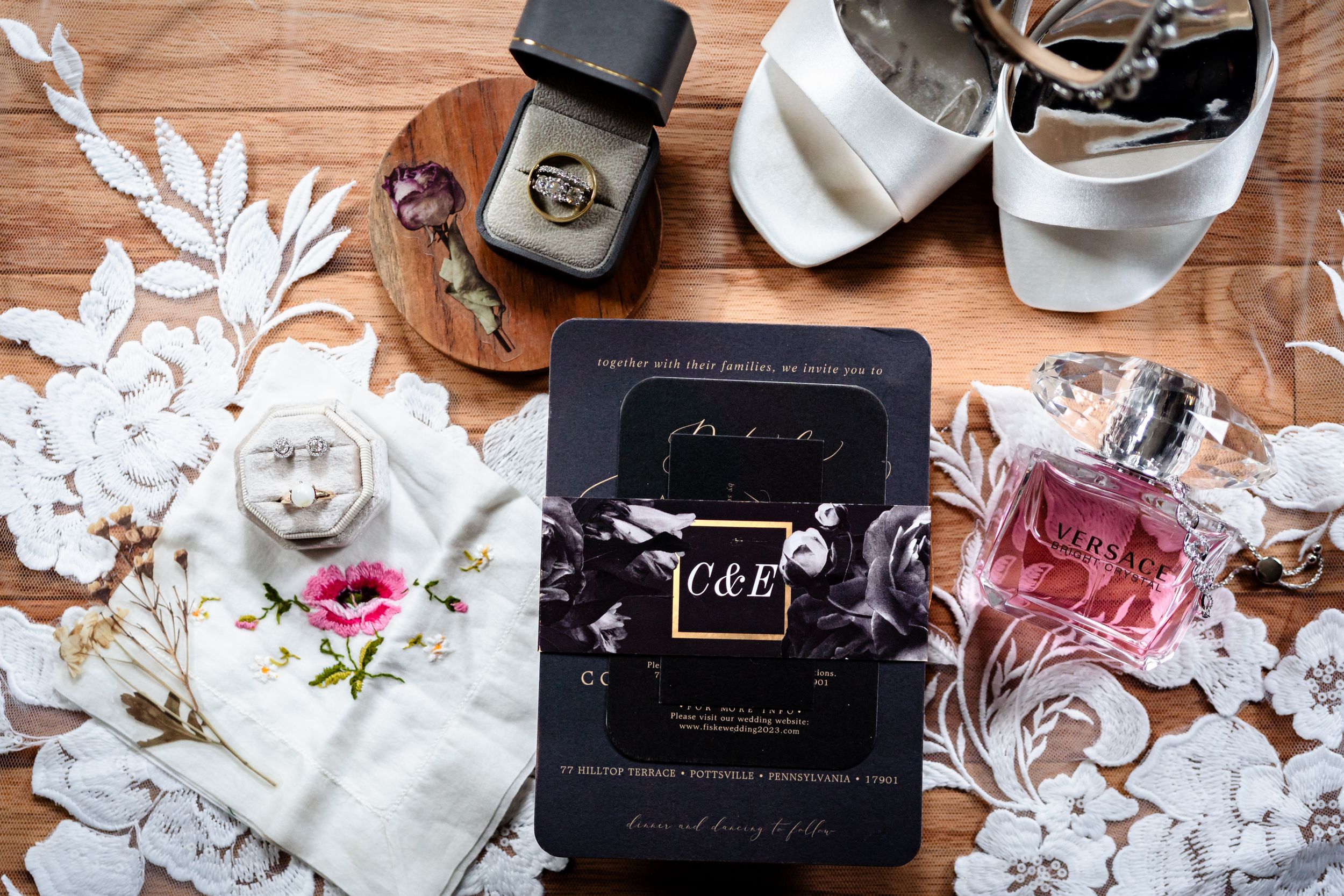 Elegant wedding details including floral arrangements and paper goods on wooden surface.