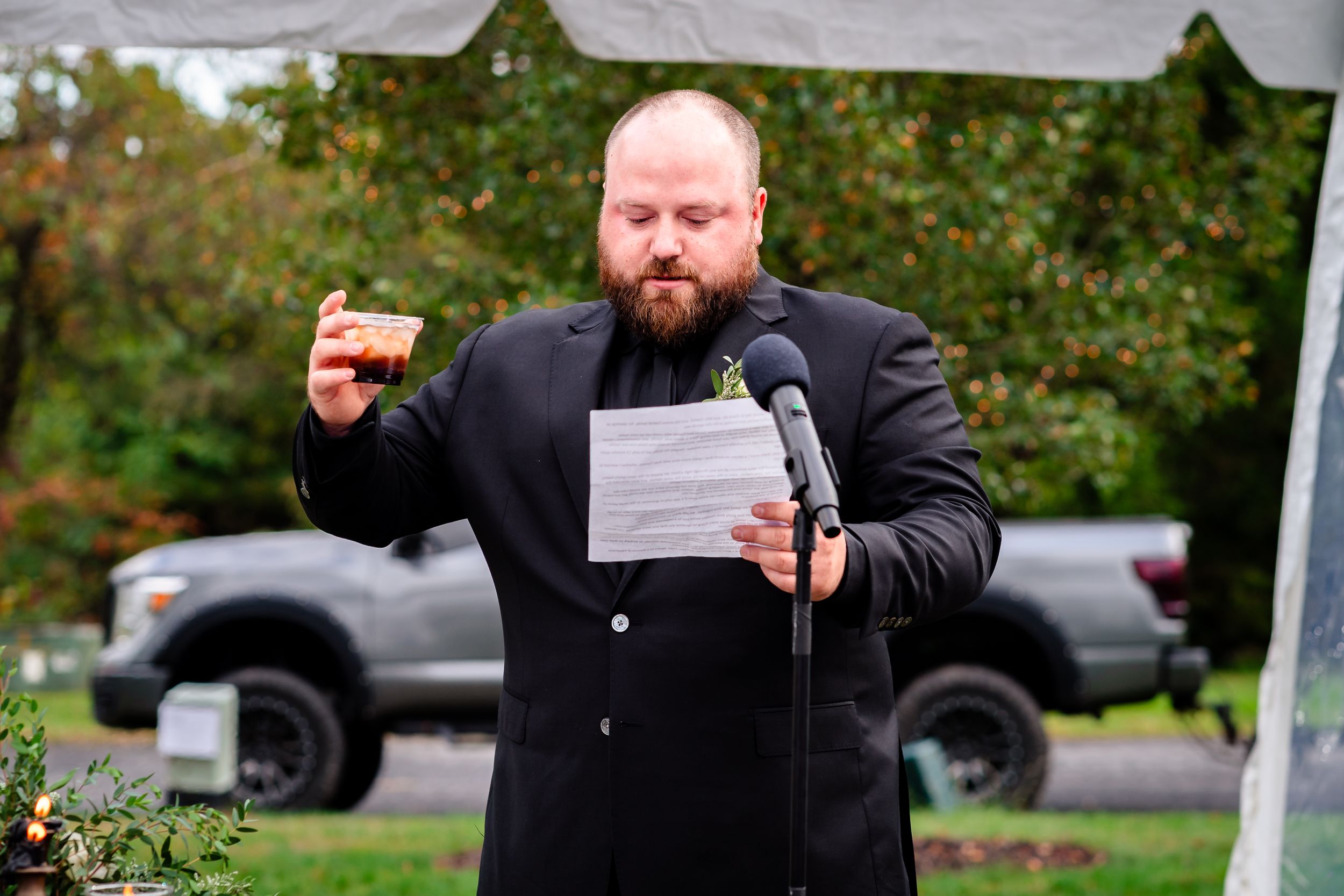 Wedding party members give heartfelt speeches during an outdoor reception celebration.
