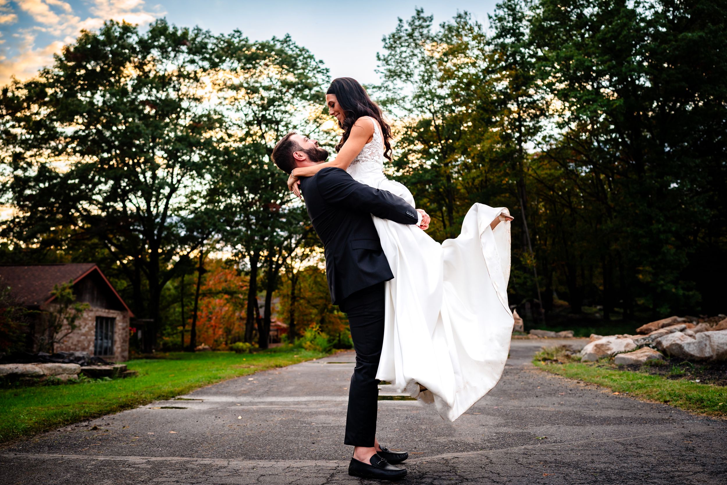 Newlyweds share romantic moments on a scenic driveway during sunset photo session.