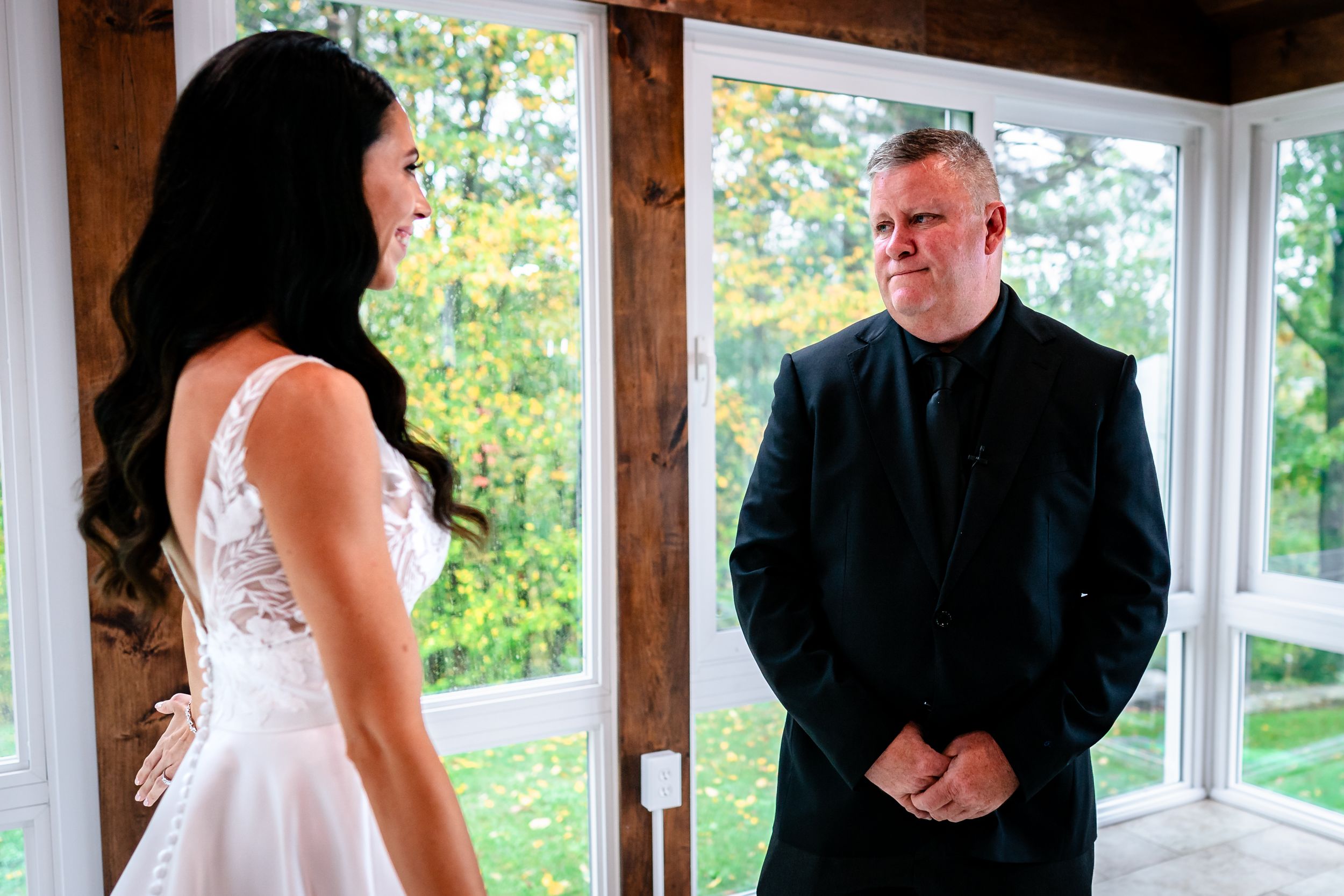 Wedding couple shares intimate moment in sunlit room with wooden beams.