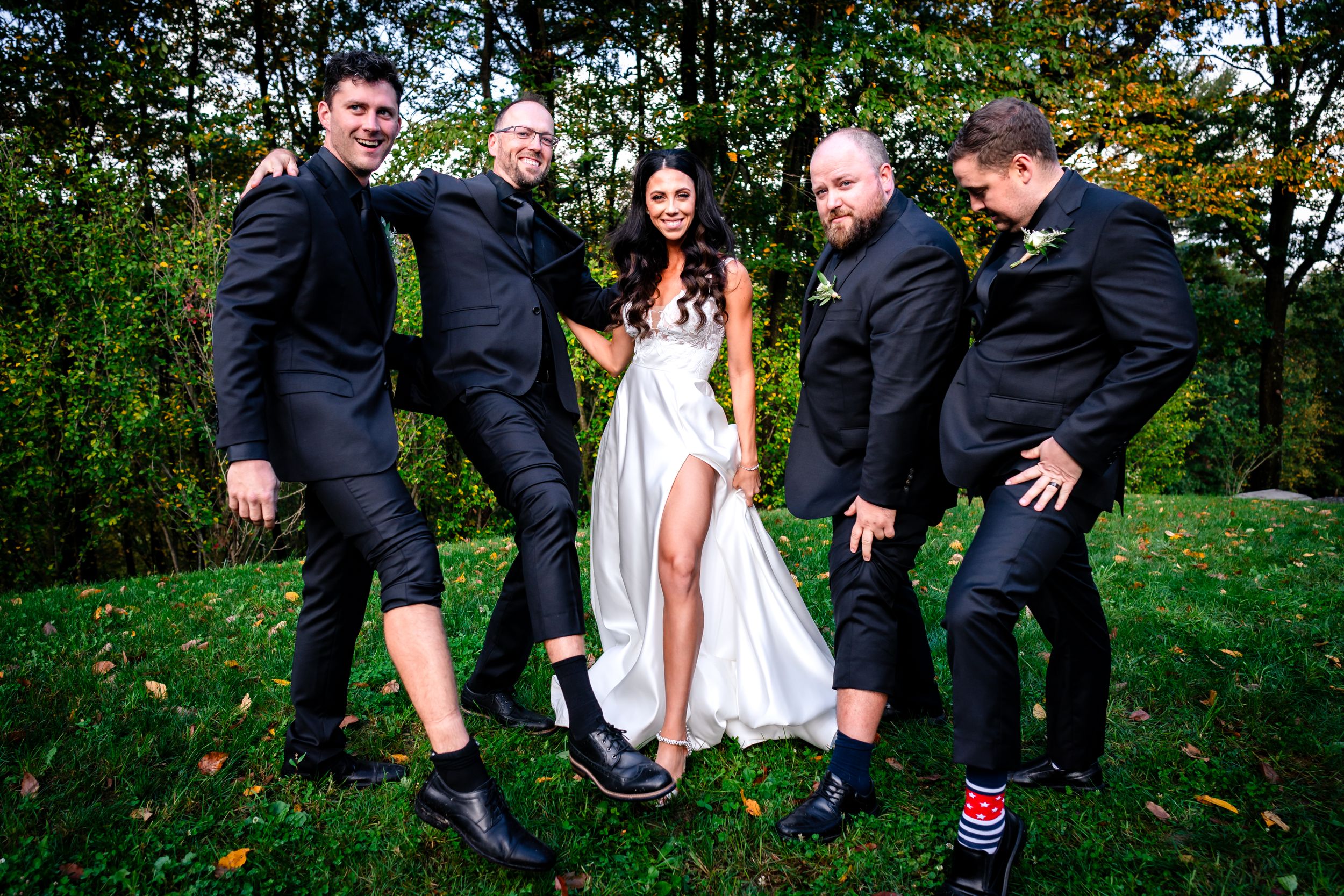 Wedding party shares candid laughs together in an outdoor garden setting.