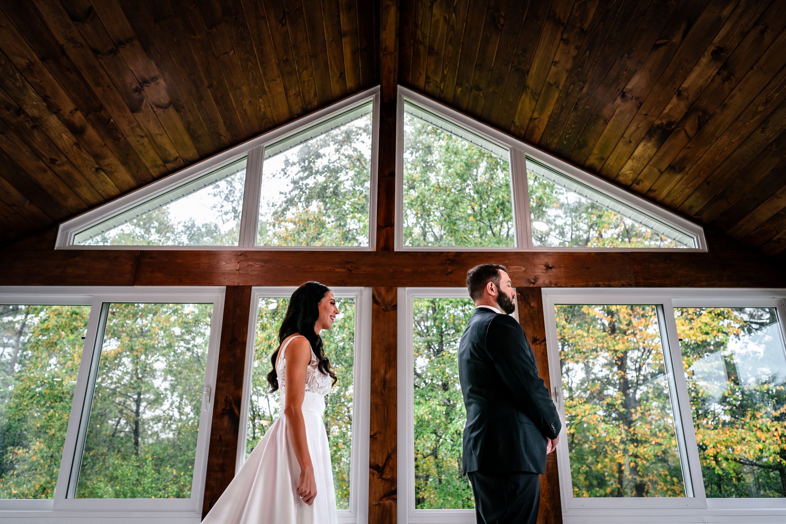 Panoramic view of rustic wedding venue with wood ceiling and wall-to-wall windows.